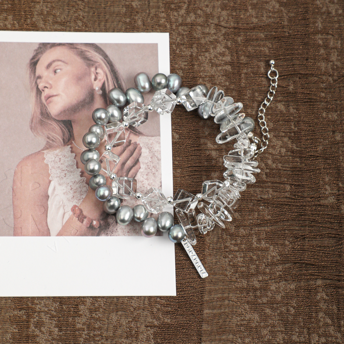 Gray pearl and clear quartz bracelet styled on brown fabric