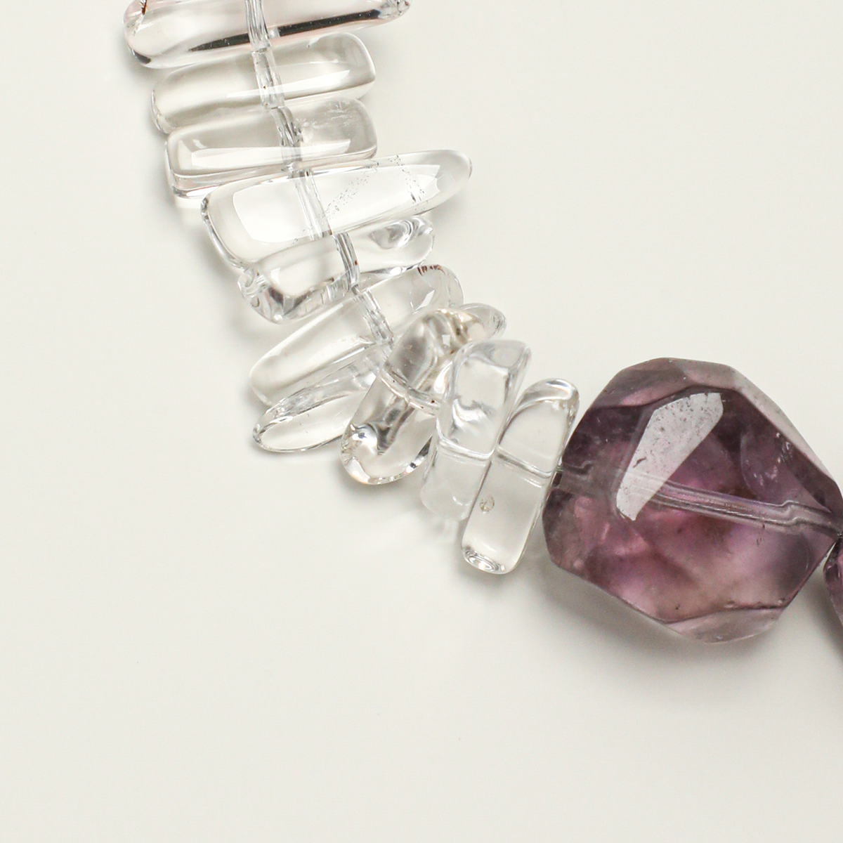 Elongated clear quartz stones beside amethyst