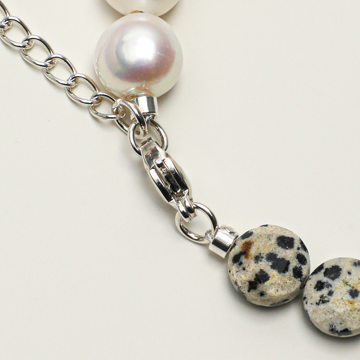 Silver-plated 316L stainless steel lobster clasp, extender chain, pearl, and spotted stone detail